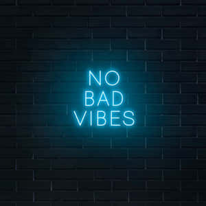 藍色霓虹燈牌寫著 no bad vibes 在深色磚牆上。