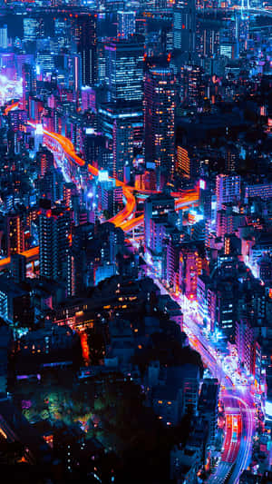 發光霓虹城市的夜間鳥瞰圖，有繁忙的高速公路和高樓大廈。