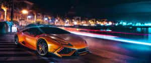 橙色跑車停泊在夜晚潮濕的城市街道上，有光跡。 — 2560x1080 壁紙