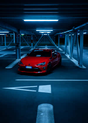 紅色跑車停放在光線昏暗、帶有藍色霓虹燈的地下車庫中。 — OnePlus Pad 壁紙