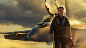 穿著飛行裝備的機師在日落時站在戰鬥機旁。 — 頂尖飛行員： Maverick 壁紙