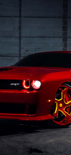 夜間停在磚牆前的紅色Dodge Challenger SRT，黃色輪圈。 — Vivo V60e 壁紙