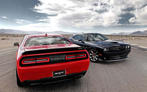 兩輛Dodge Challenger SRT肌肉車停泊在沙漠公路上，背景有山脈。
