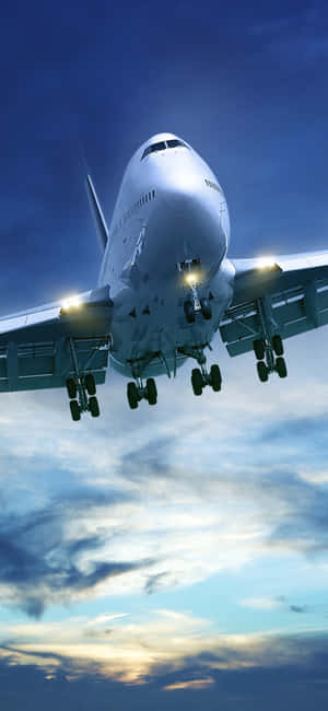 一架大型客機在黃昏天空下亮著燈準備降落。