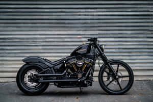 黑色Harley-Davidson電單車，金色細節，停泊在金屬車庫門前。 — 機車 壁紙