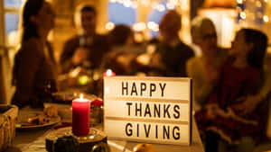 一張感恩節晚餐桌，點燃的蠟燭和「Happy Thanksgiving」標誌被家人環繞。