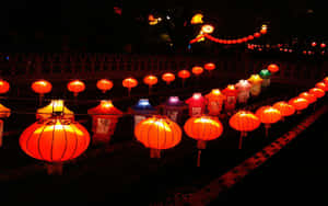 一串發光的紅色燈籠在夜晚照亮了一條黑暗的小路。 — 中國新年 壁紙