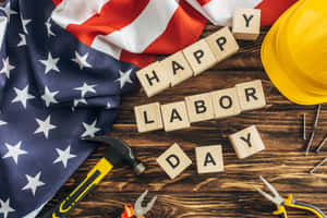 用木塊拼出的Happy Labor Day，旁邊有美國國旗和工具。