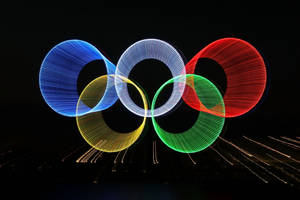在黑暗中由光軌和火花創造的奧運五環。