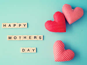 用木製拼字磚和三個紅色圖案心形在藍色上拼出的 Happy Mothers Day。