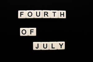 白色字母瓷磚在黑色背景上拼出 fourth of july
