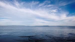 廣闊的海景，遠處有島嶼和縷縷白雲，藍天。