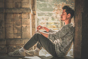 年輕男子在溫暖陽光下靠著石柱沉思。