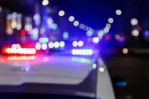 夜間警車燈光閃爍紅藍色，帶有模糊的城市燈光。