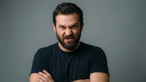 留鬍子的男人交叉雙臂做出憤怒表情的攝影棚照