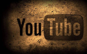 在溫暖聚光燈下，粗糙混凝土牆上繪製的 YouTube 標誌。