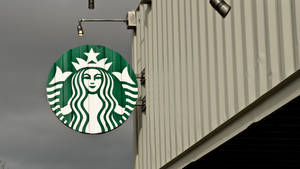 Starbucks標誌牌掛在金屬建築上，灰色天空