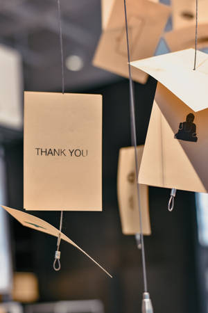 現代室內裝飾中懸掛的米色紙卡，上面有「THANK YOU」和剪影。