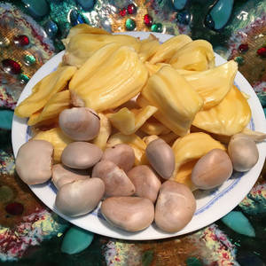 白色碟子盛載菠蘿蜜果肉和種子，置於彩色珠子背景上。