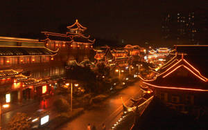 傳統中國建築在夜間沿著城市街道被橙色燈光照亮。 — 唐人街 GIF 壁紙