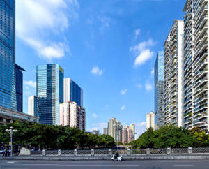 城市街道，高樓林立，一輛滑板車在晴朗的藍天下駛過。