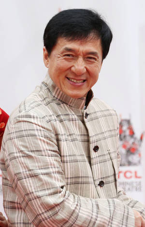 一位在公共活動中穿著格紋襯衫微笑的男士。 — 荷里活 GIF 壁紙