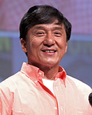成龍在公開活動中身穿紅白格仔恤衫微笑。 — 粉紅 壁紙