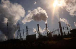 工廠煙囪在有電線的陽光天空下釋放煙霧。 — 黃昏 壁紙