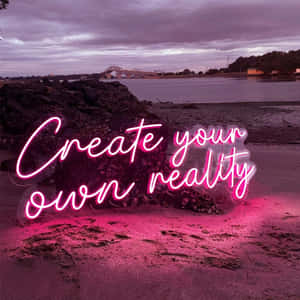 黃昏時分海灘上一個粉紅色霓虹燈牌，寫著「Create your own reality」。