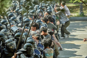 抗議者在陽光明媚的街道上與身穿防暴裝備的警察對峙。