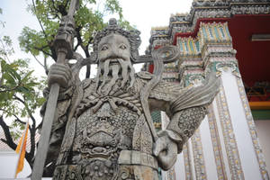 裝飾華麗的寺廟中的守護神石像，有綠樹和色彩繽紛的建築。