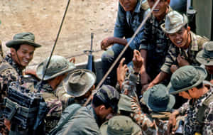 穿著迷彩裝備的士兵在塵土飛揚的戶外環境中微笑互動。
