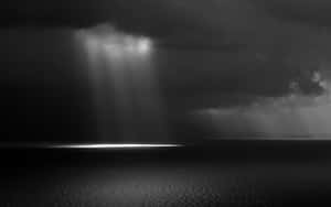 陽光穿透暴風雲，照射在黑暗的水面地平線上。 — 暮光 壁紙
