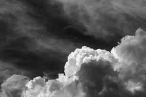 戲劇性的灰階雲層，在黑暗暴風雨的天空襯托下，呈現明亮蓬鬆的結構。 — MacBook Air M2 壁紙