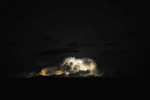 在黑暗山丘上方的繁星夜空背景下，被閃電照亮的發光暴風雲。 — MacBook 壁紙