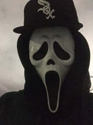戴著 Ghostface 面具、身穿黑色連帽衫和棒球帽的人。