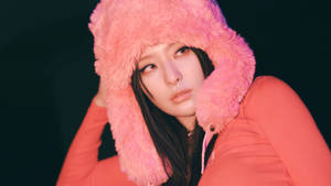 穿著粉紅色毛絨連帽外套的女性在昏暗光線中側視。