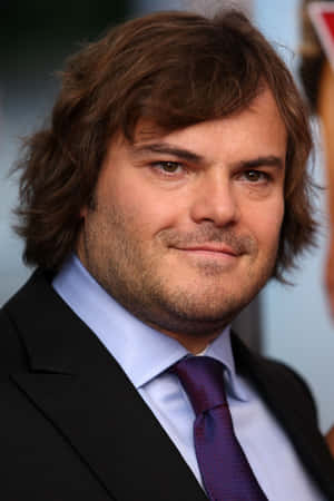 Jack Black 著住西裝同領呔對住鏡頭微笑。 — Huawei MatePad Edge 壁紙