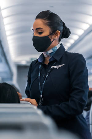 空中服務員戴口罩在飛機上服務乘客