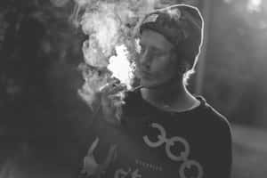 戴冷帽的人士在戶外黑白背景下呼出煙霧。 — 食草 壁紙