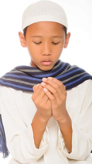 祈禱中的小男孩，雙手合十，閉著眼睛，戴著白色頭巾和藍色圍巾。