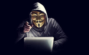 戴着蓋伊·福克斯面具的人指着黑暗房間裏的手提電腦。 — 鬼滅之刃面具 壁紙