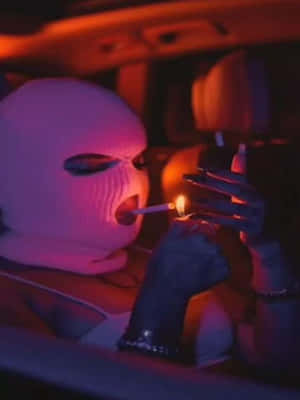 戴白色滑雪面罩嘅人喺有霓虹燈嘅車入面點煙。