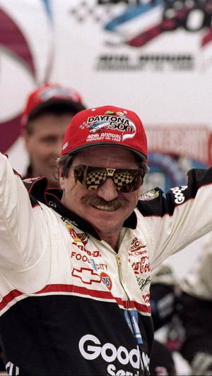 NASCAR車手在Daytona 500高舉雙臂，戴著格子太陽眼鏡慶祝勝利。