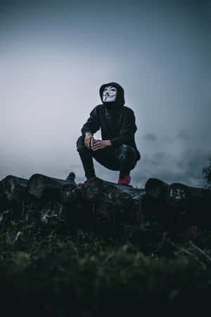 匿名人物戴著面具蹲在霧氣瀰漫的戶外環境中的木頭上。 — 鬼滅之刃面具 壁紙