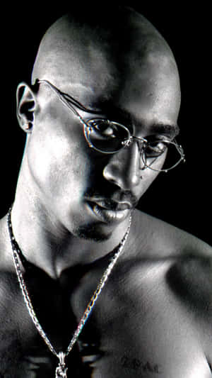Tupac Shakur 在黑白工作室肖像中戴著眼鏡和鏈條。