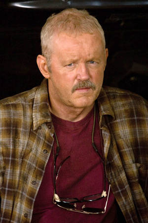 一位留著鬍子、眼鏡掛在襯衫上的男子看起來很嚴肅。