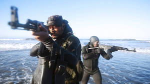兩名身穿潛水衣的武裝士兵涉水穿過海浪。