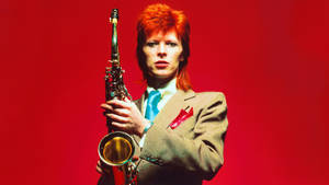 David Bowie 身穿西裝，在紅色背景下拿著色士風。