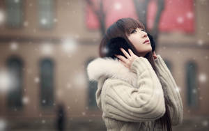 穿著冬季大衣的女子在城市中仰望飄落的雪